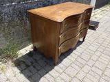 une commode en bois à trois tiroirs posée au bord de la rue