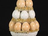 a white vase with eggs in it on a black background