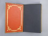 an open book with a red cover sitting on top of a table