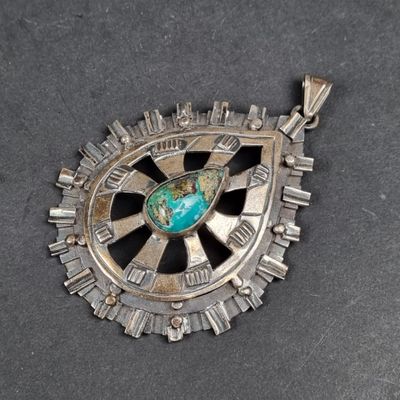 une image représentant un pendentif en argent orné d'une pierre turquoise au centre