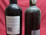 two bottles of wine sitting next to each other on a red background
