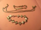 un collier et un bracelet en argent posés sur un fond rose