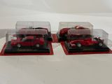 three red cars in a display case on a white surface