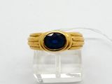 Gros plan sur une bague en or ornée d'une pierre bleue