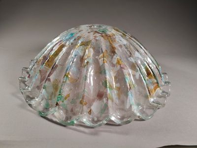 un objet en verre en forme de coquille posé sur une surface blanche