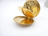 a gold pocket watch sitting on a white surface