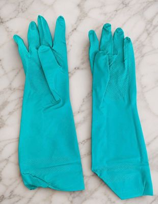 une paire de gants en caoutchouc bleus posés sur une surface en marbre