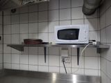 un micro-ondes posé sur une étagère métallique dans une cuisine