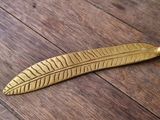 a gold feather shaped object sitting on top of a wooden floor