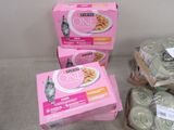 three boxes of cat food sitting on top of a table next to cans of cat food