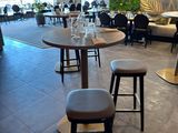 tables and stools in a restaurant with a wall of greenery behind them