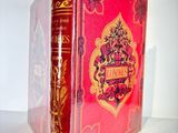 an old red book sitting on top of a table next to a white wall