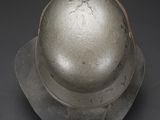 an old metal helmet with a metal cap on a black background