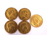 five gold coins of different sizes and shapes on a white surface