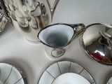 a white table with silver dishes and a silver tea pot