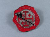 a red and silver pin with a chinese symbol on it