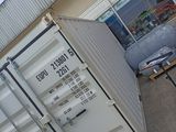a white container sitting outside of a building with a blue door