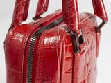 the red handbag is sitting on a white surface with a zipper
