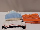 three hats and a scarf sitting on top of a white table