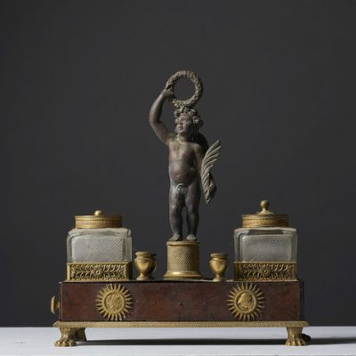 une figurine antique en bronze représentant un Cupidon tenant une couronne