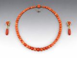 un ensemble composé d'un collier et de boucles d'oreilles en perles orange, avec un fermoir doré