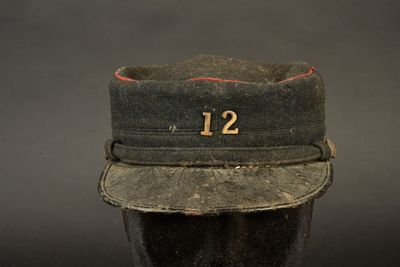 un chapeau noir portant le numéro 12, posé sur la tête d'un mannequin