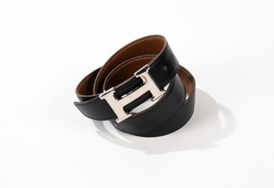 une ceinture en cuir noir avec une boucle argentée sur fond blanc