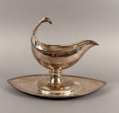 an antique silver plate with a bird shaped saucer on it