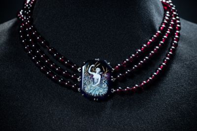 purple and black beaded necklace with a bird pendant on a mannequin
