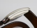 the back of a watch with a leather band and a silver clasp