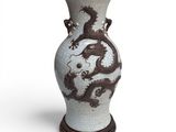 un vase orné d'un dragon, posé sur un socle