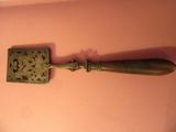 un petit objet en laiton posé sur une surface rose, près d'un mur rose