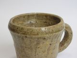 a brown cup with a handle on a white surface