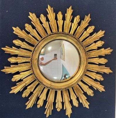 a gold sunburst mirror hanging on a blue wall
