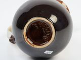a black vase with a brown handle on a white surface