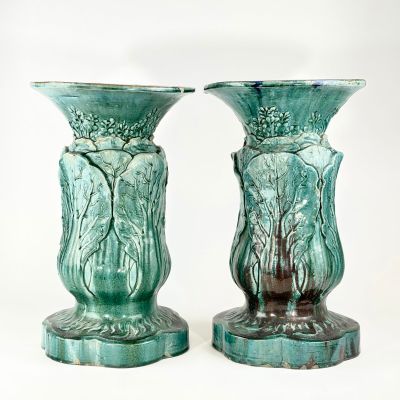 deux vases verts posés l'un à côté de l'autre sur une surface blanche