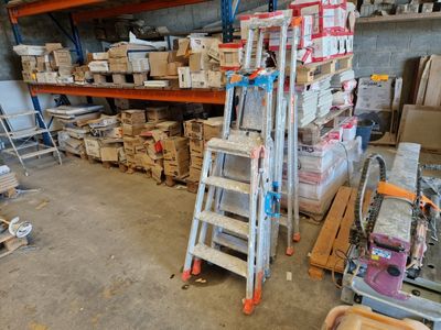 une échelle posée dans une pièce, sur laquelle sont empilés de nombreux cartons