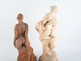 two statues of a man and a woman sitting on a rock