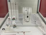 many different necklaces and bracelets on display in a glass case