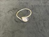 a gold ring with a white stone on the sand