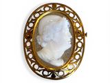 an image of a picture of a woman ' s face in a gold broocher