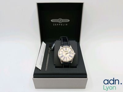 une photo d'une montre dans un coffret, posée sur une surface blanche