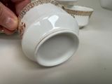 a person that is holding a cup and saucer on a table