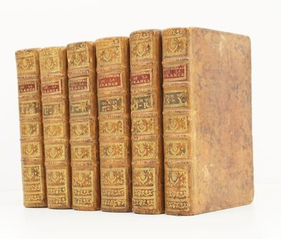 quatre vieux livres posés l'un sur l'autre sur une surface blanche