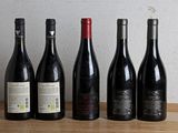 several bottles of wine are lined up on a wooden table