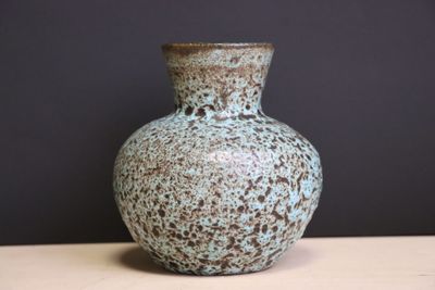 un vase bleu posé sur une table, sur fond noir