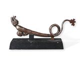 une sculpture métallique représentant un lézard posé sur un socle en bois