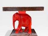 un éléphant rouge qui se tient debout sous une table