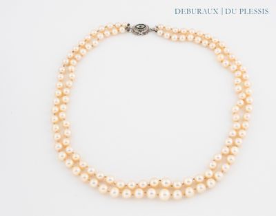 a close up of a necklace with pearls on a white surface