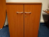 une armoire en bois à deux portes et une planche de surf posée par terre